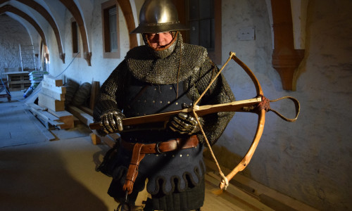 Restaurator Jens Klocke führt in der stilechten Kleidung eines mittelalterlichen Armbrustschützen vor, wie eine solche Waffe funktionierte. Foto: Stadt Goslar
