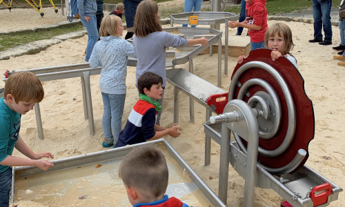 Wasser und Sand: Kinder weihen die neue Matschanlage im Kurpark offiziell ein, während Karin Jünke, Heinrich Wilgenbus und Dr. Oliver Junk das Treiben beobachten. Foto: Stadt Goslar