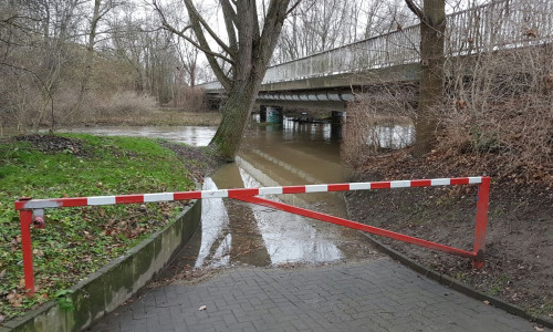 Einige Wege und Flächen entlang der Oker stehen unter Wasser. Hier: Brücke unterhalb der Friedrich-Ebert-Straße mit der Schranke und Blick Richtung Groß Stöckheim. Foto: Feuerwehr Wolfenbüttel
