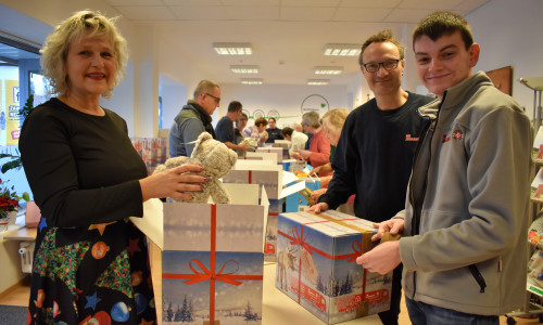 Die Johanniter Susanne Felka, Thomas Hartmann und Nico Müller (von links) packen gemeinsam mit an, um die Kartons für den Weihnachtstrucker zu packen. Foto: Johanniter-Unfall-Hilfe e.V.