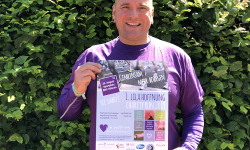 Der 1. Vorsitzende des Vereins "Lila Hoffnung" präsentiert das Plakat für seinen Charity Run. 
