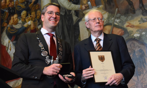 Dr. Oliver Junk und Kay Nehm zeigen auf der Bühne in der Kaiserpfalz Urkunde und Ehrenplakette, die die Stadt Goslar dem langjährigen VGT-Präsidenten verliehen hat. Foto: Stadt Goslar