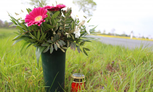 Ein Blumenstrauß und eine Grableuchte erinnern an den schweren Motorradunfall vom letzten Wochenende. Foto: Sandra Zecchino / Audio: aktuell24/bm