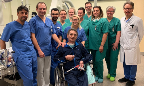 Umringt vom kardiologischen Team: Ralf Rohrbeck, hält in seiner Hand die Herzpumpe, die seine Herzfunktion unterstützt hat, während er sich von einem Herzinfarkt erholte. Foto: Helios