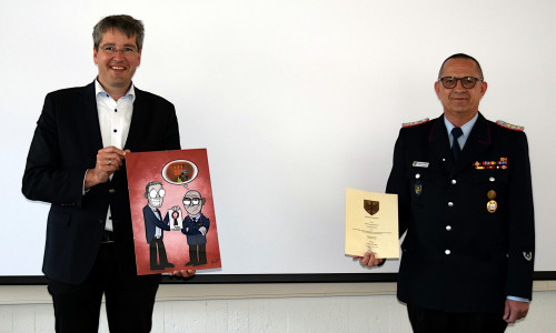Stadtbrandmeister Christian Hellmeier (rechts) nimmt von Oberbürgermeister Dr. Oliver Junk Urkunde und Geschenk entgegen.