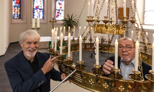 Pastor Uwe Teichmann und Elektromeister Herbert Lindhofer mit dem alten Kronleuchter in der Kirche. 