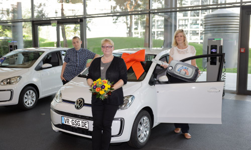 Amanda Busch und ihr Sohn Sohn Dustin Wiener können es noch nicht so richtig glauben. Sie nahmen einen neuen VW e-Up! von Nicole Pschak, Privatkundenberaterin bei der Volksbank BraWo (rechts), in der Autostadt Wolfsburg in Empfang. 