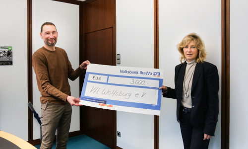 Stephan Ehlers, Geschäftsführer des VfL Wolfsburg e.V., nimmt den Spendenscheck von Claudia Kayser, Leiterin der Direktion Wolfsburg der Volksbank BraWo, entgegen.