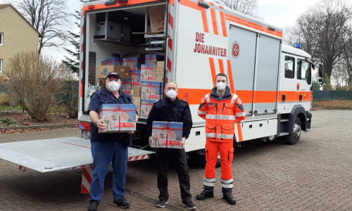 Manfred Wäldchen von der Freiwilligen Feuerwehr Beinum und Ortsbrandmeister Hartmut Stern freuen sich, dass sie Nils Meier von den Johannitern Pakete für Bedürftige mitgeben können.