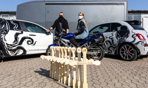 Die Elf Holzkreuze stehen für die Verstorbenen in der Motorradsaison 2020. Im Hintergrund: Marc Kiefer, Geschäftsführer des Messebauers MR - Die Manufaktur und Tina Wachter, stellvertretende Vorsitzende des ACM.