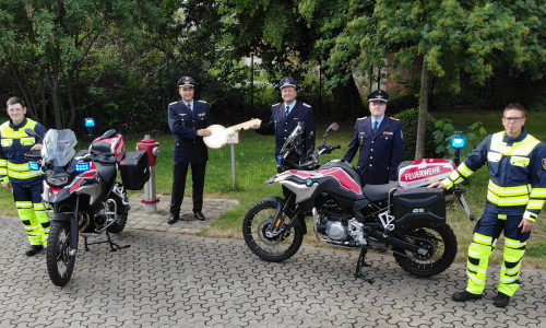 Kreisbrandmeister Tobias Thurau (2.v.l.) übergibt zwei Motorräder an Michael Hesse (3.v.l.) und Michael Pförtner (4.v.l.). 