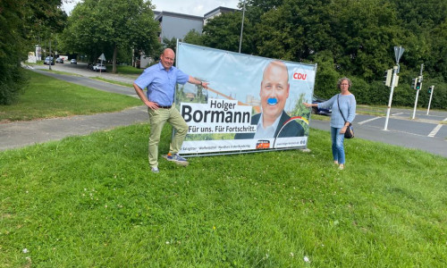 Holger Bormann und Andrea Kempe vor dem beschmierten Plakat.