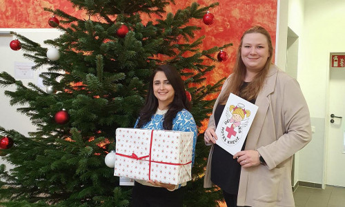 Die Migrationsberaterinnen Laila Refai (links) und Frederike Schwieger präsentieren ein Geschenk und den neu entworfenen DRK-Weihnachtsengel - symbolisch für die neue Aktion, die sich die Rotkreuzler für Kinder aus bedürftigen Familien ausgedacht haben.