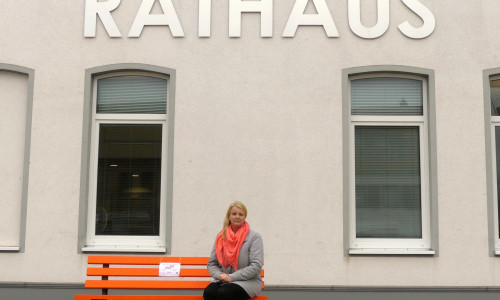 Die Gleichstellungsbeauftragte Kathrin Drost auf der orangenen Bank vor dem Rathaus der Gemeinde Vechelde.