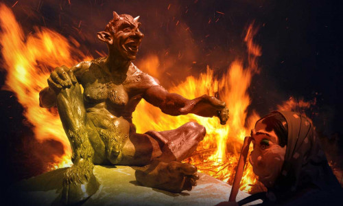 Der Teufel sitzt auf einem Stein beim Hexentanzplatz in Thale und schaut den Hexen beim Tanzen zu.