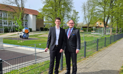 Bürgermeister Tobias Grünert (li.) und Ortsbürgermeister Olaf Marotz begutachten den neuen Zaun am Jugendplatz an der Hildesheimer Straße.