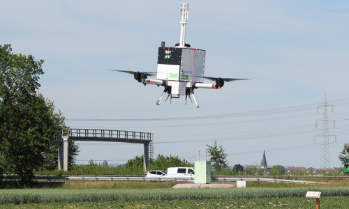Die MesSBAR-Drohne im Einsatz an der A 555 bei Wesseling. Im Hintergrund ist die Schadstoff-Messstation der Bundesanstalt für Straßenwesen zu sehen.