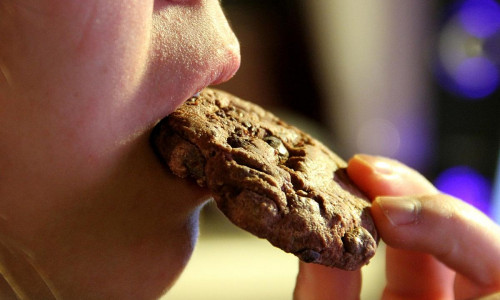 Junges Mädchen isst einen Schokoladenkeks (Archiv)