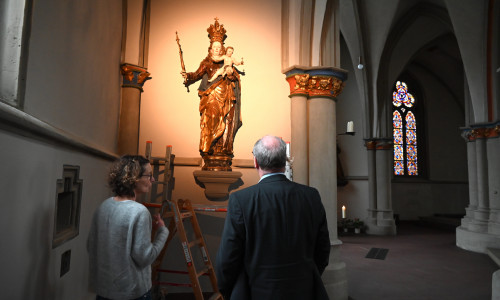 Dipl.-Restauratorin Jutta Knörle und Propst Martin Tenge mit der frisch restaurierten frühbarocken Marienfigur in der Andachtskapelle des Chorumgangs in St. Aegidien. 