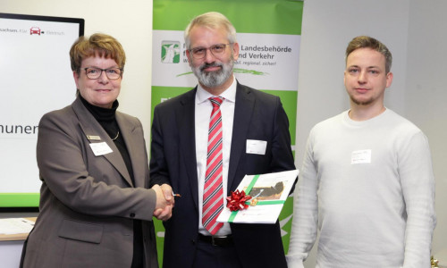 Ute Spieler, Kreisrätin für Umwelt, Bau und Schule des Landkreises Gifhorn, und Jonathan Hartmann, Mobilitätsmanager beim Landkreis Gifhorn (rechts), nahmen von Timo Quander, Präsident der Niedersächsischen Landesbehörde für Straßenbau und Verkehr, die Ausbaustrategie für die öffentliche Ladeinfrastruktur in Empfang. 