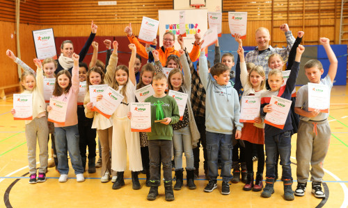 Die Kinder freuen sich über ihre Siegerurkunden, 250 Euro Preisgeld für die Klassenkasse und den Pokal.