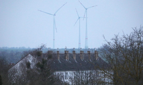 Ein Mehrfamilienhaus mit Windrädern im Hintergrund am 09.03.2024