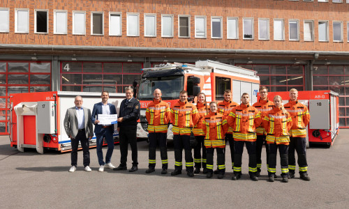 Jens-Folker Huismann und Christoph Mrasek von der Öffentlichen bei der Scheckübergabe an Torge Malchau und die aktuellen Auszubildenden der Braunschweiger Feuerwehr (von links nach rechts).