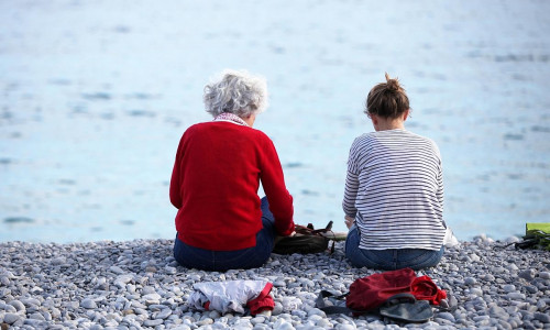 Alte und junge Frau sitzen am Strand