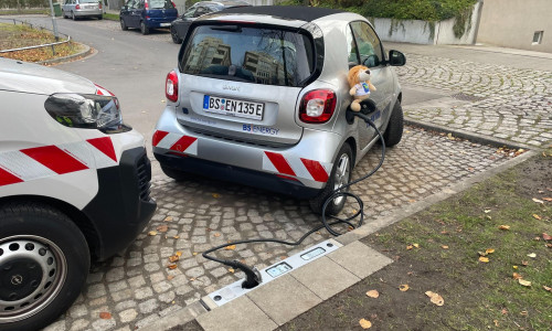 Der Ladevorgang eines Elektrofahrzeugs über den Bordstein.