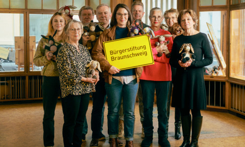 Maria Meibohm (mit Schild, Buchhandlung Graff) steht gemeinsam mit Ehrenamtlichen der Bürgerstiftung Bürgerstiftung im zukünftigen MitMachEck der Stiftung. In den Händen halten die Ehrenamtlichen selbstgenähte Esel, die das Projekt „LEsel unterwegs – Die Rucksackbibliothek“ unterstützen.