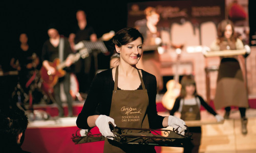 Die Schokoladen-Botschafter servieren während des Konzerts die live auf der Bühne zubereiteten Schokoladen-Pralinen. 