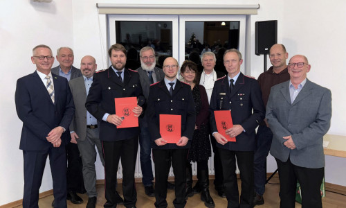 Dirk Neumann, ganz links, mit den Feuerwehrmännern (v. l.) Kevin Müller, Alexander Jacob und Peter Thiele, eingerahmt von Rats- und Verwaltungsmitgliedern.