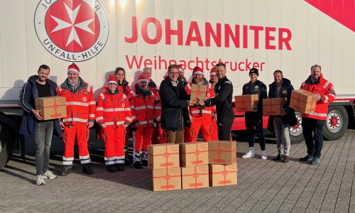 Eintrachts Co-Trainer Marc Pfitzner übergibt eines der elf Pakete an Johanniter-Landesvorstand Hannes Wendler. Bildnachweis: Johanniter/Lena Kopetz.