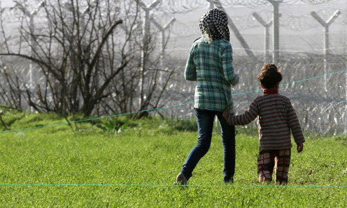 Flüchtlinge vor einem Grenzzaun (Archiv)