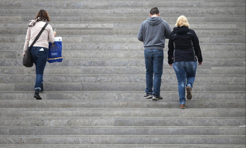 Drei Personen gehen eine Treppe hinauf (Archiv)