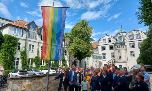 Erster Kreisrat Dominik Meyer zu Schlochtern, Vertreterinnen und Vertreter des Queeren Netzwerks Gifhorn und zahlreiche Gäste hissten die Regenbogenflagge vor dem Schloss Gifhorn.
