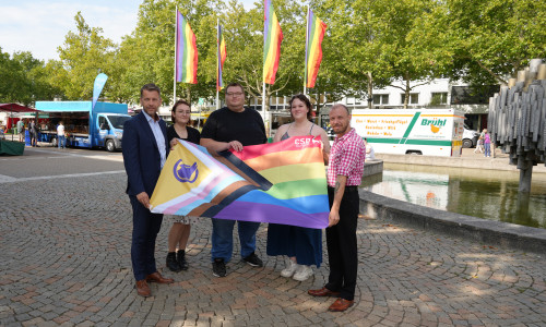 Oberbürgermeister Dennis Weilmann und Britta Deike (Gleichstellungsreferat Stadt Wolfsburg) präsentieren gemeinsam mit den Organisatoren des CSD Wolfsburg - Luke Bärthel, Isabell Kleindienst und Kevin Kluge - die offizielle Flagge (v. li.).