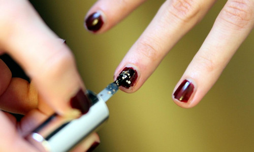 Frau lackiert Fingernägel mit Nagellack (Archiv)
