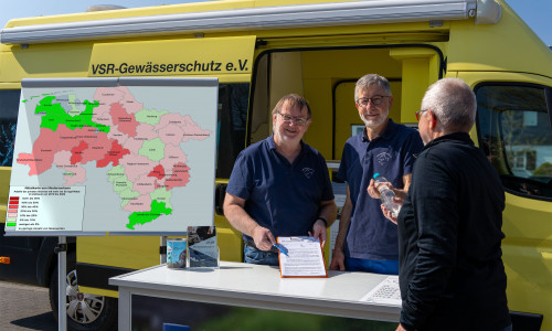 Arno Mittelmeyer und Heinz-Theo van Wickeren beraten einen Brunnenbesitzer mit Nitratkarte Niedersachsen vor einem Labormobil des VSR-Gewässerschutz e.V..