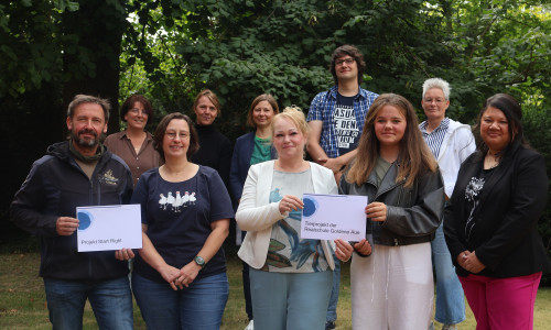 Die Vergabekommission für „… die paar Cent!“, bestehend aus (hintere Reihe im Bild, von links) Katja Sdralek, Nicole Schwarzenberger, Stephanie Schwarz, Sascha Riedl und Birgit Römer, überreicht die Spendengelder  Die vordere Reihe zeigt die Projektverantwortlichen sowie die Mitarbeiterinnen des Landkreises Goslar, die jeweils diese Vorschläge eingereicht haben (von links): Thomas Derer („Start Right“), Christine Lipinski, Isabel Barfus, Charlotte Böttger (beide verantwortlich für das Tierprojekt der Goldenen Aue), und Jacqueline Diercks.