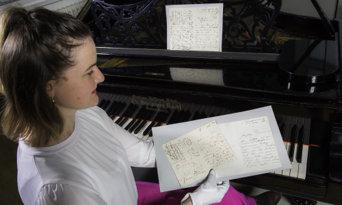 Dr. Antje Becker mit einer Auswahl an Clara Schumann-Autographen am Flügel der Pianistin.