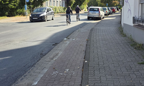 Die Radfahrer müssen links an dem im Parkverbot stehenden Kleinwagen vorbeifahren, da die Zufahrt zum Radweg erst dahinter verläuft.