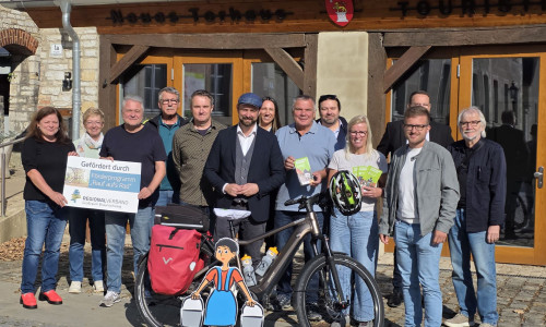 Bürgermeister Malte Schneider (Mitte)  mit den Projektbeteiligten die Schönin- ger Radnadel vor der Schöninger  Touristmusinformation im Torhaus.