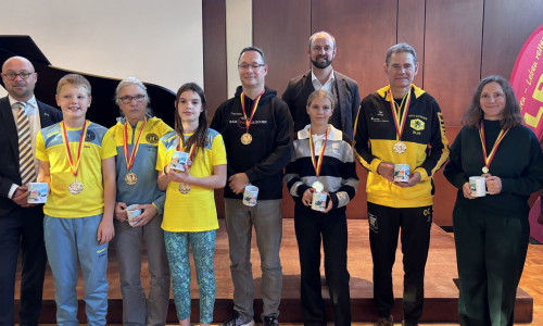 Enno Deuter, Vorsitzender der DLRG-Ortsgruppe Schöningen, und Bürgermeister Malte Schneider (2. Reihe) mit den Champions des 12-Stunden-Schwimmens 2026. 
