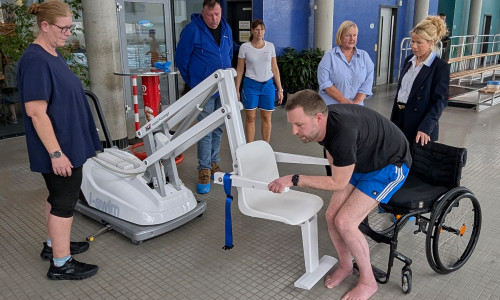 Premiere im Aquantic: Björn Lehrke-Ahrens nimmt im Beisein von Oberbürgermeisterin Urte Schwerdtner (v. re.), Andrea Simon, Behindertenbeauftragte der Stadt Goslar, und Meik Erbrecht (2. v. li.), Technischer Leiter des Bäderbetriebs, sowie zwei Schwimmmeisterinnen auf dem neuen Schwimmbadlifter Platz.