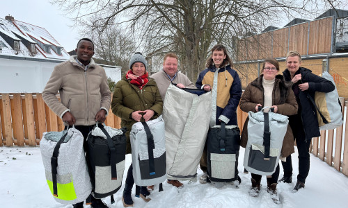 Desire Bararunyeretse (Tagestreff), Sabine Rieck (Ambulante Hilfe), Marc Wegner (Johanniter-Hilfsgemeinschaft), Ragnar Petzke und Alissa  Wittenfeld (beide Tagestreff), Nadine Boß (Regionalleitung Diakonische Gesellschaft Wohnen und Beraten) - Mitarbeiter im Tagestreff, Ragnar Petzke, präsentiert den Sheltersuit – Jacke, Schlaf- und Rucksack.