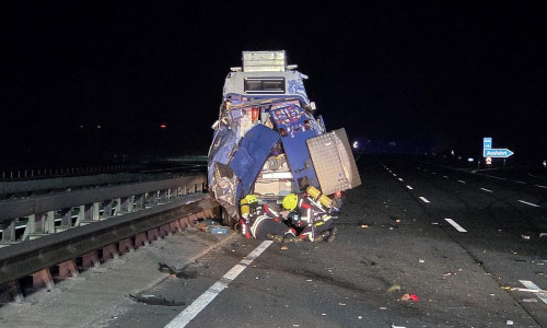 Die Feuerwehr unter Atemschutz an einem beschädigten Fahrzeug (Archiv)