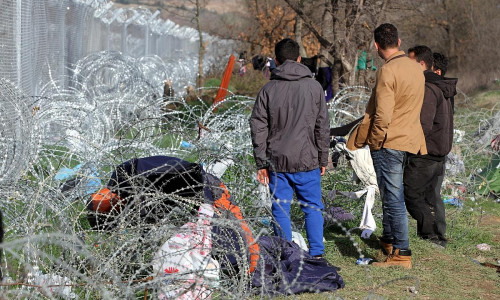 Flüchtlinge auf der Balkanroute vor einem Grenzzaun (Archiv)