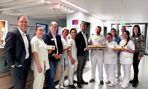 (von links) Der stellvertretende Klinikumsdirektor Jörg Reinhardt, Pflegedirektorin Christiane Bitter, Wolfsburgs Oberbürgermeister Dennis Weilmann, und Lynn Erle aus dem Team Pflegedirektion verteilten anlässlich des Internationalen Tages der Pflegenden süßes Gebäck an die Mitarbeitenden auf den Stationen und in den Funktionsbereichen des Klinikums. Das Foto zeigt sie gemeinsam mit dem Team der Station G6a.