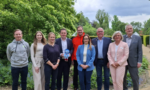 Bei der Vorstellung der Studienergebnisse (von links): Roy Präger vom VfL Wolfsburg, Marleen Stridde von der Audi BKK, Studienkoordinatorin Melanie Lemke vom Universitätsklinikum Hamburg-Eppendorf, Landrat Philipp Raulfs, Miroslav Jenka, Trainer bei den Grizzlys, Projektleiterin Janine Ahrends von der Gesundheitsförderung und Prävention des Landkreises Gifhorn, Norbert Blyszcz, Vorstandsmitglied der Young Grizzlys Wolfsburg, Nele Westphal, Fachbereichsleiterin Kinder, Jugend und Familie beim Kreisverband Gifhorn des Deutschen Roten Kreuzes, und Kreisrat und Gesundheitsdezernent Rolf Amelsberg. Landrat Philipp Raulfs hält das Maskottchen Tobi des Bewegungsprojekts in den Händen. 